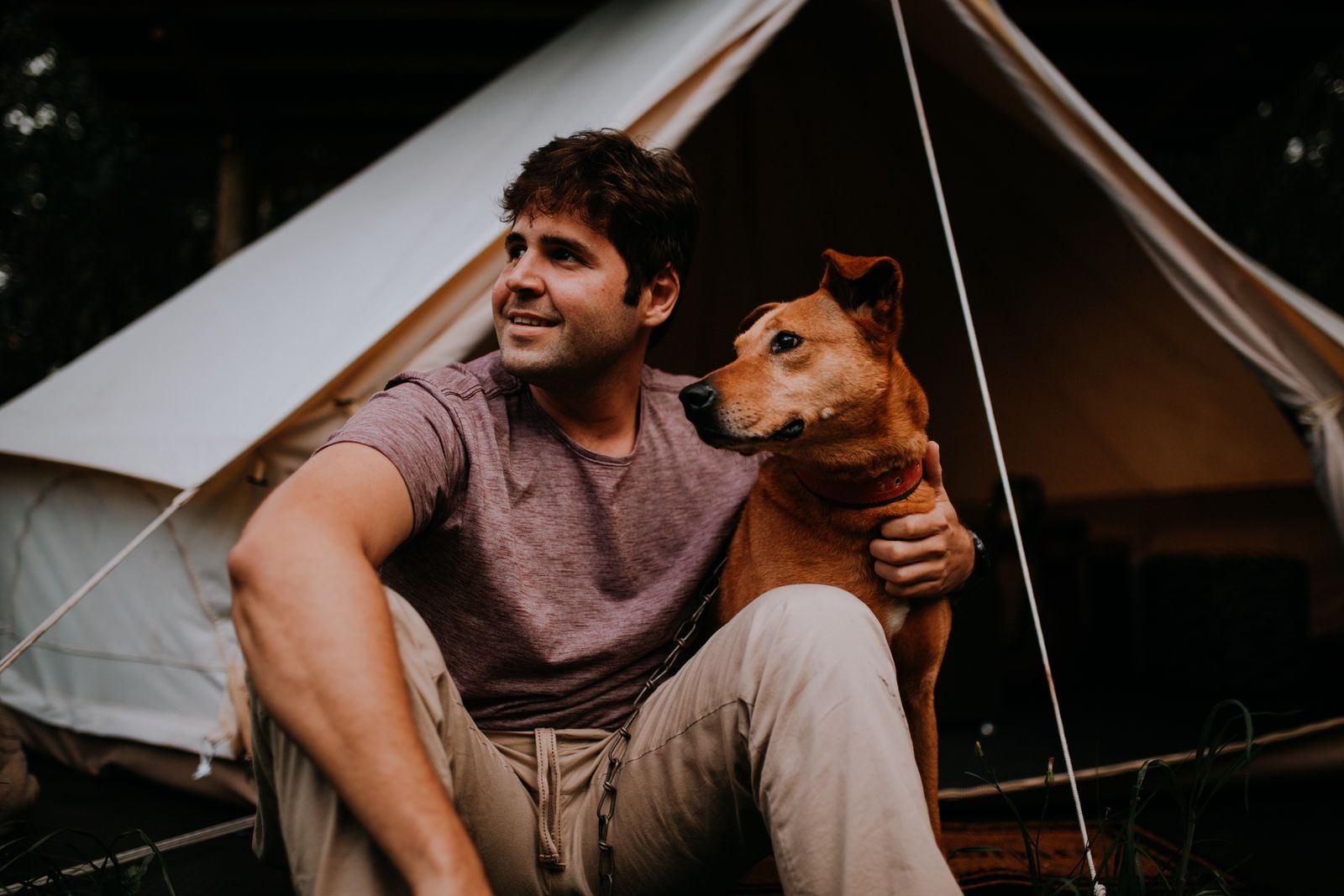 A guest sitting with his dog outside a bell tent at a glamping site