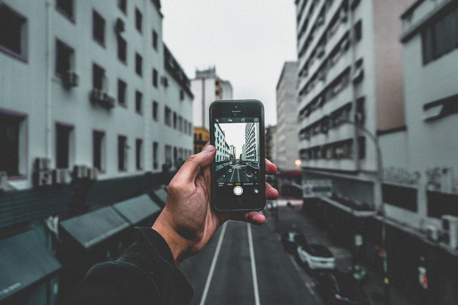 A traveller holding up a smartphone to a city street, consulting it to navigate
